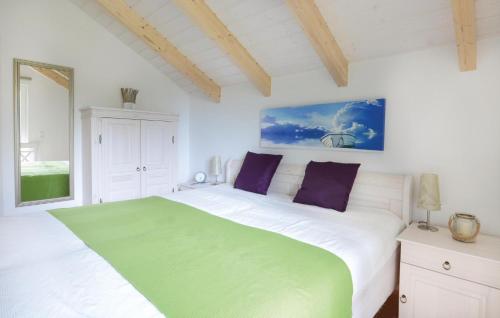 ein weißes Schlafzimmer mit einem grünen und weißen Bett in der Unterkunft Seeteufel in Süssau