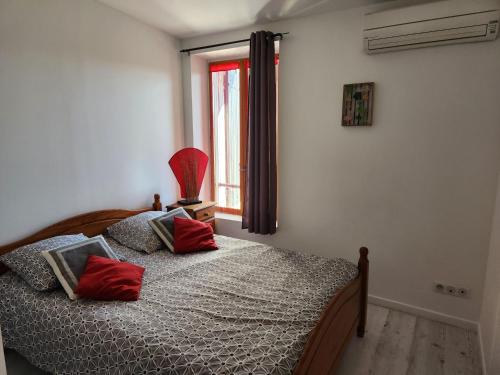 MeynesにあるChemin de la Carquetteのベッドルーム1室(赤い枕のベッド1台、窓付)