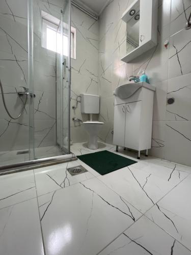 a white bathroom with a shower and a sink at ALOHA apartment in Novi Pazar