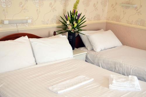 a room with two beds and a potted plant at Lyndene Hotel in Blackpool