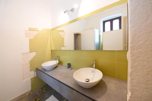 a bathroom with two sinks and two mirrors at Masseria Peppeturro in Cisternino