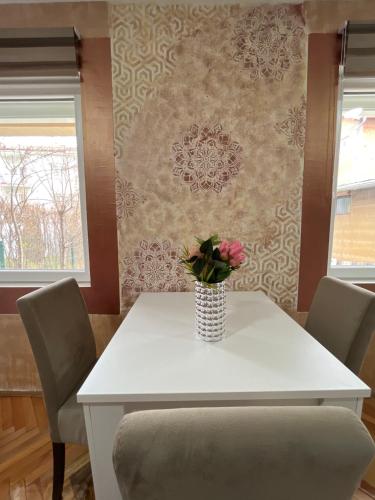 a white table with a vase of flowers on it at ALOHA apartment in Novi Pazar