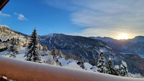 a view of a snowy mountain with the sun in the background at Chalet Baumfuchs direkt an der Talabfahrt Belalp in Blatten bei Naters