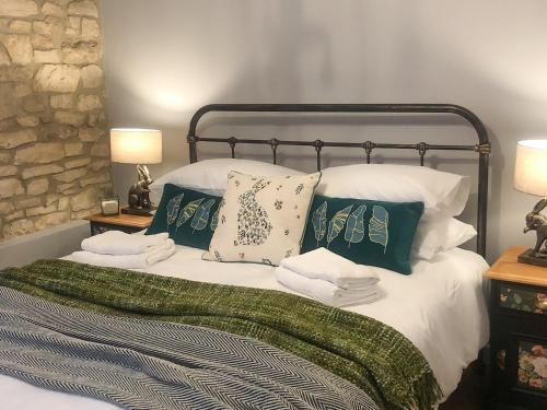 a bed with green and white pillows and two lamps at The Street Cottage in Uley