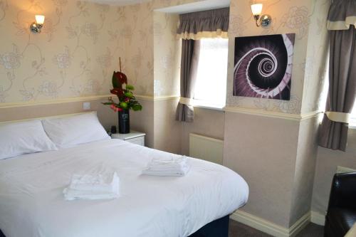 a bedroom with a large white bed with a window at Lyndene Hotel in Blackpool