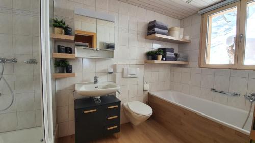 a bathroom with a sink and a toilet and a bath tub at Chalet Baumfuchs direkt an der Talabfahrt Belalp in Blatten bei Naters