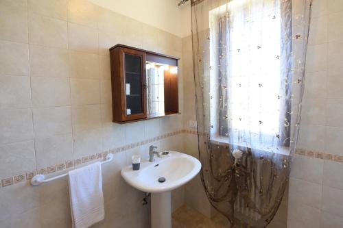 a bathroom with a sink and a mirror and a window at Masseria Peppeturro in Cisternino