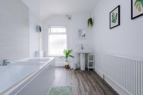 a white bathroom with a tub and a sink at Hope House Chester Sleeps 6 by Heritage Stays in Hough Green
