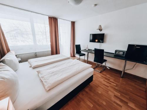 a bedroom with two beds and a desk and a television at Zentral Hotel in Bad Füssing
