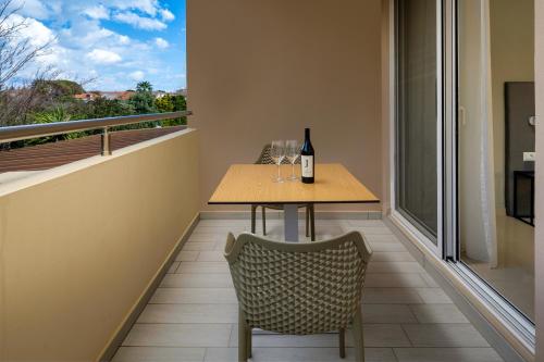 a table with a bottle of wine and a chair on a balcony at Sunday Hotel in Ialyssos