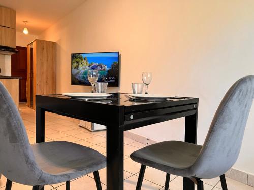 a black dining room table with two chairs and wine glasses at Le ti Canbou - Studio - Près de la plage -By Sister Home in Saint-Gilles les Bains