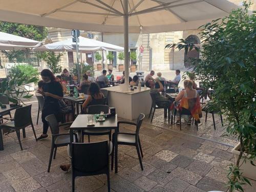 un grupo de personas sentadas en un restaurante bajo un paraguas en Dimore di Lecce - I Figuli, en Lecce