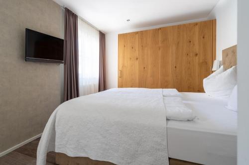 a bedroom with a white bed and a flat screen tv at Kaiser Max Design Appartements in Innsbruck