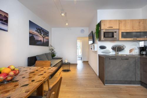 eine Küche und ein Wohnzimmer mit einem Holztisch im Zimmer in der Unterkunft Apartman Oliva in Krk