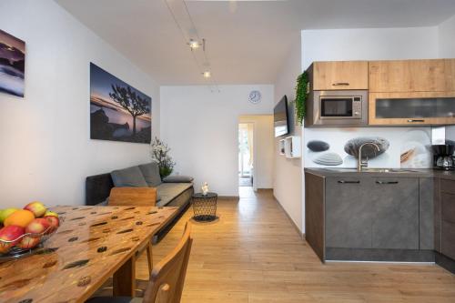 a kitchen and living room with a wooden table in a room at Apartman Oliva in Krk