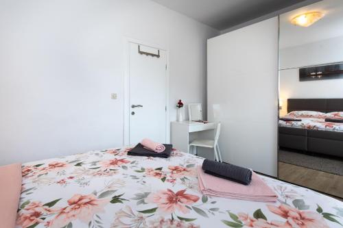 ein Schlafzimmer mit einem großen Bett mit einem rosa Blumenmuster in der Unterkunft Apartman Oliva in Krk