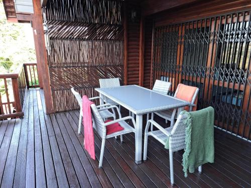 een tafel en stoelen op het terras van een hut bij Eagles Call in Port Edward