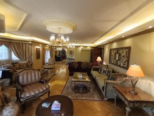 een woonkamer met meubilair en een kroonluchter bij Luxury Apartment In Massaken Sheraton near Cairo Int'l Airport in Caïro
