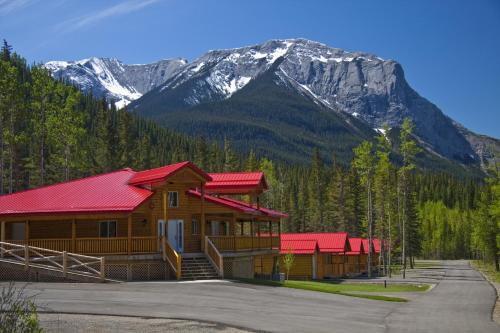 a log cabin with red roofs in front of a mountain at Jasper East Cabins in Jasper
