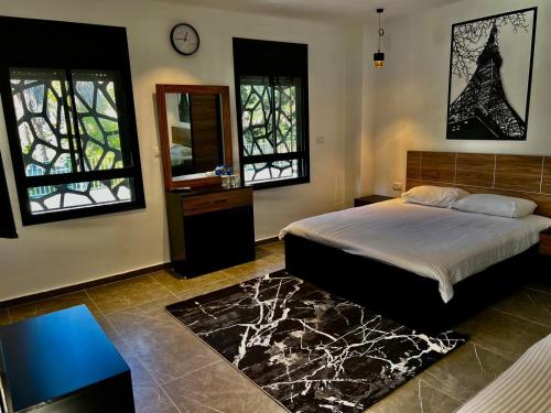 a bedroom with a bed and a mirror and windows at ZOZO Guesthouse in Nazareth