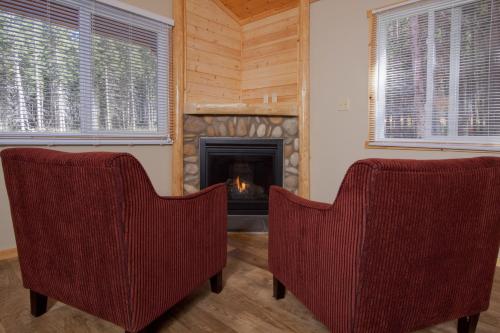 two chairs in a living room with a fireplace at Jasper East Cabins in Jasper