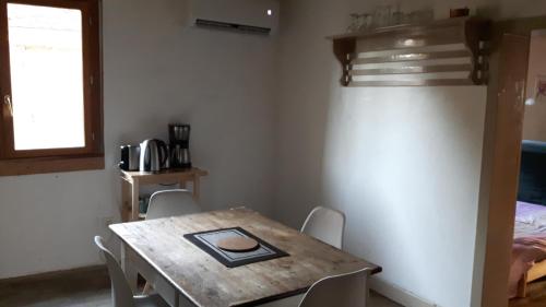 d'une salle à manger avec une table, des chaises et une fenêtre. dans l'établissement Chaleureuse petite maison avec jardin, à Gagnac-sur-Cère