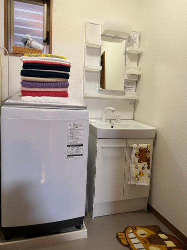 a small bathroom with a sink and a white refrigerator at Guest House Kubo Homes Matsu in Osaka