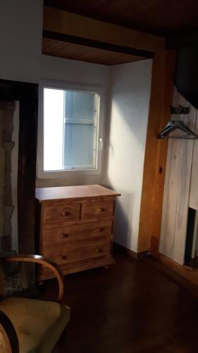 - une chambre avec une commode en bois et une fenêtre dans l'établissement Chaleureuse petite maison avec jardin, à Gagnac-sur-Cère
