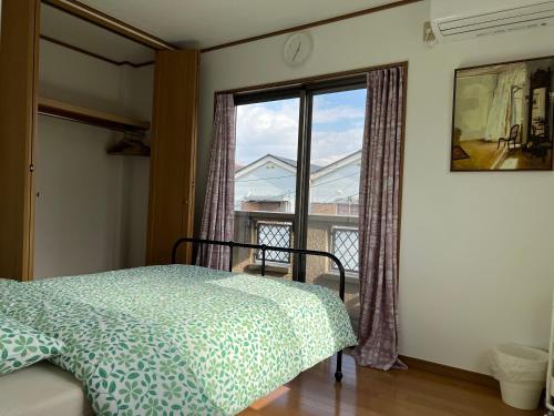 Guest House Kubo Homes Matsu في أوساكا: غرفة نوم بسرير ونافذة كبيرة