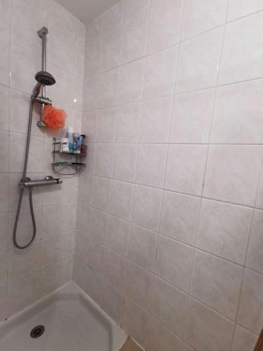 La salle de bains est pourvue de carrelage blanc, d'une douche et d'une baignoire. dans l'établissement Frontignan au Clair de plage, à Frontignan