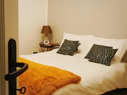 a bed with black and white pillows and a yellow blanket at ArtGallery Apartment - Villa immersa nel verde - Deluxe in Viterbo