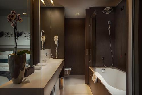 a bathroom with a tub and a toilet and a sink at Hotel Cubo in Ljubljana