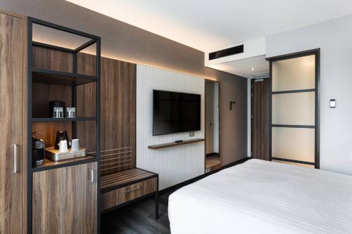 a bedroom with a bed and a flat screen tv at Courtyard by Marriott Amsterdam Airport in Hoofddorp