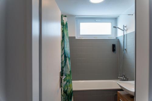 ein Bad mit einer Badewanne, einem Waschbecken und einem Fenster in der Unterkunft Green-Art-Living: NEW BOHO Style Central für 2 in Kempten