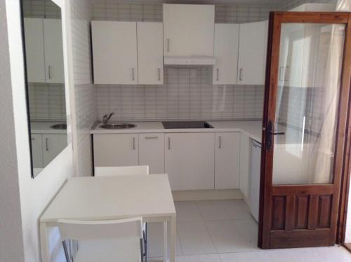 a kitchen with white cabinets and a table and a door at Casa Blanca Suiza in Benissa