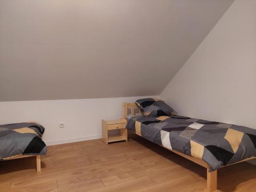 2 Betten in einem Zimmer mit weißen Wänden und Holzböden in der Unterkunft Pokoje Kraków Tyniec in Krakau