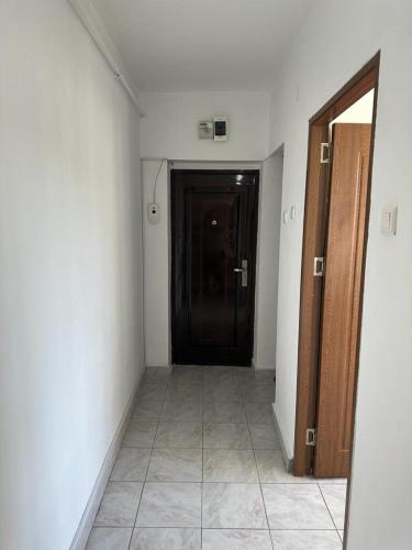 a hallway with a black door and a tile floor at Velovan Apartment in Craiova