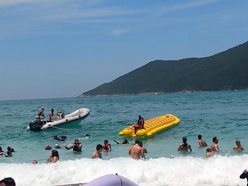 a group of people in the water at the beach at Apartamento no Golden Lake - pé na areia, agua de côco e cervejinha in Arraial do Cabo