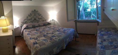 a bedroom with a bed and a window at VILLETTA CON SPIAGGIA PRIVATA ALLE DUNE in Castiglione della Pescaia