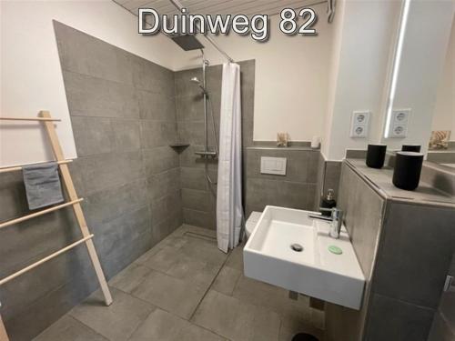 een badkamer met een wastafel, een douche en een toilet bij Appartementen Zuiderstrand in Westkapelle