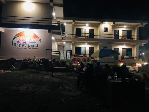 a group of people sitting under an umbrella in front of a building at Hotel Happy Land in Chitwan