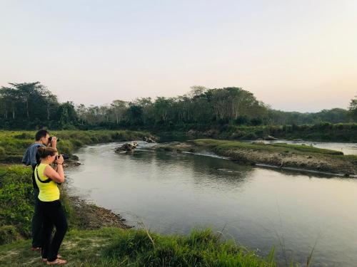 a woman taking a picture of a river at Hotel Happy Land in Chitwan