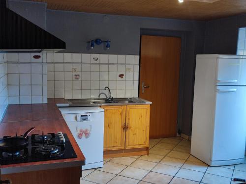 eine Küche mit einem Herd und einem weißen Kühlschrank in der Unterkunft Chambre Haut in Zilling
