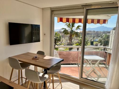 een eetkamer met een tafel en een groot raam bij Les Capitelles 97 - Studio vue mer - residence avec pisicne in Saint-Cyprien