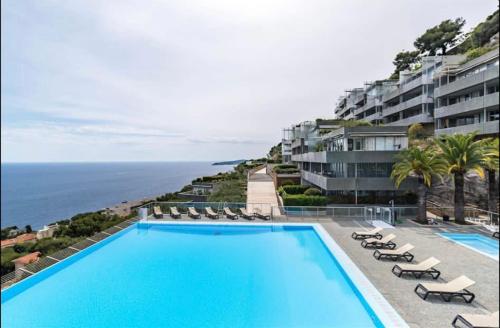 einen Pool mit Stühlen und das Meer im Hintergrund in der Unterkunft Luxueux appartement - vue mer - piscine - free parking - Monaco in Cap d'Ail