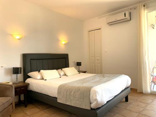 - une chambre avec un grand lit et des draps blancs dans l'établissement Le Catalan, à Banyuls-sur-Mer