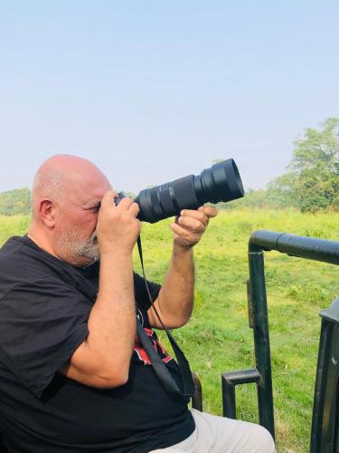 a man is looking through a camera with a telescope at Hotel Happy Land in Chitwan