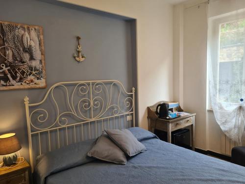 a bedroom with a bed with a blue blanket and a window at Pippo a Vernazza Rooms in Vernazza