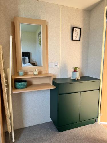 a bathroom with a green vanity and a mirror at Fieldview 43 in Leysdown-on-Sea