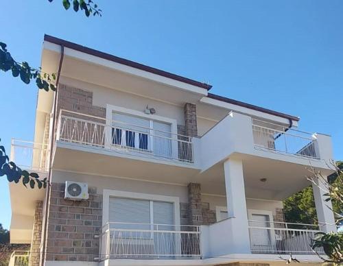 Appartamento 150 mq in villa sul mare a Fertilia في فيرتيليا: بيت ابيض كبير فيه بلكونات وبلكونه